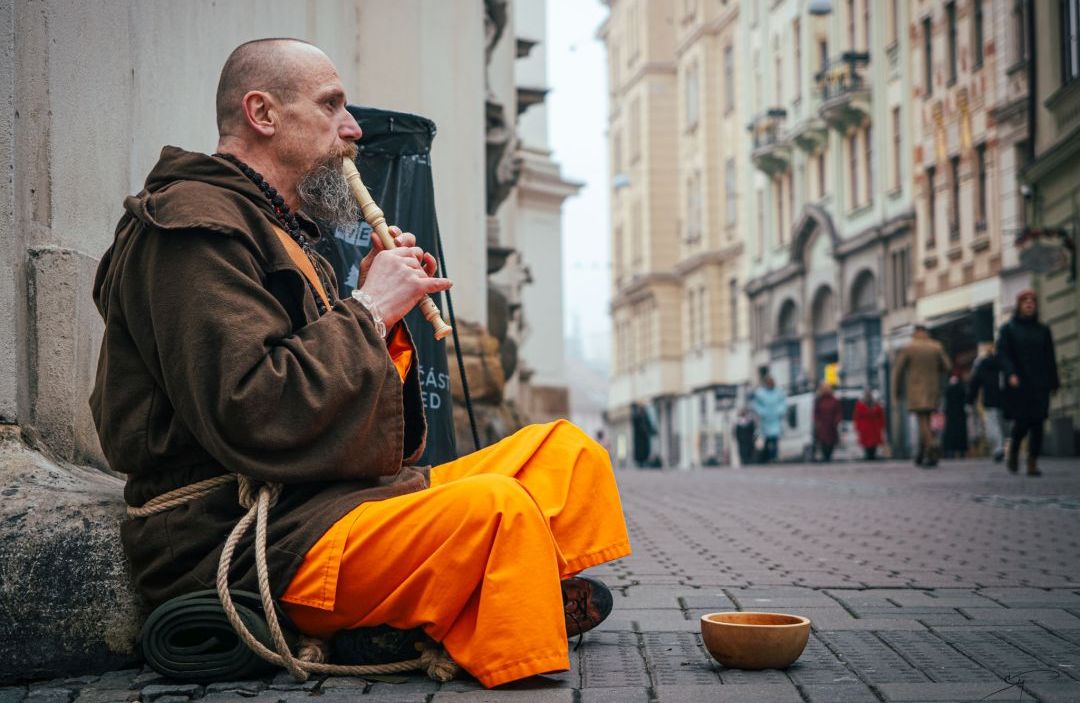 Svámí Gyaneshwarpuri hrající jako pouliční muzikant na flétnu před Minoritským chrámem v Brně. Foto: Tomáš Sukup (2025).