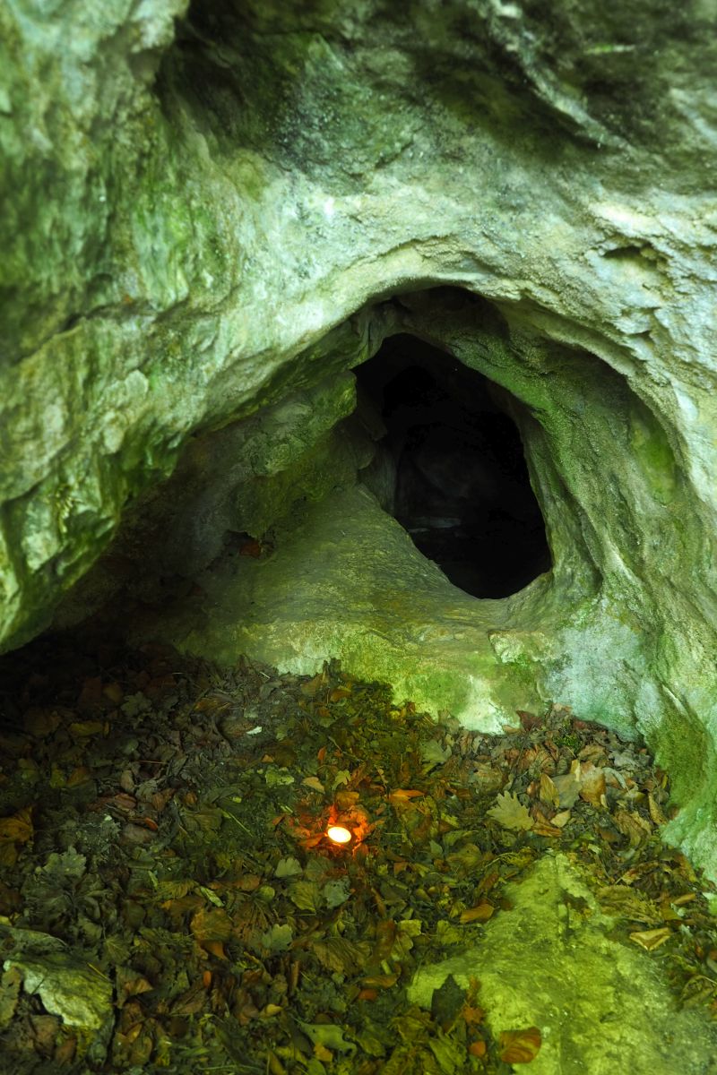 Jeskyně Slezákova díra - Záhrobní. Vchod jeskyně v místě dětského neolitického hrobu (označeno plamenem svíčky). Foto: Marek Gyaneshwarpuri (2020).